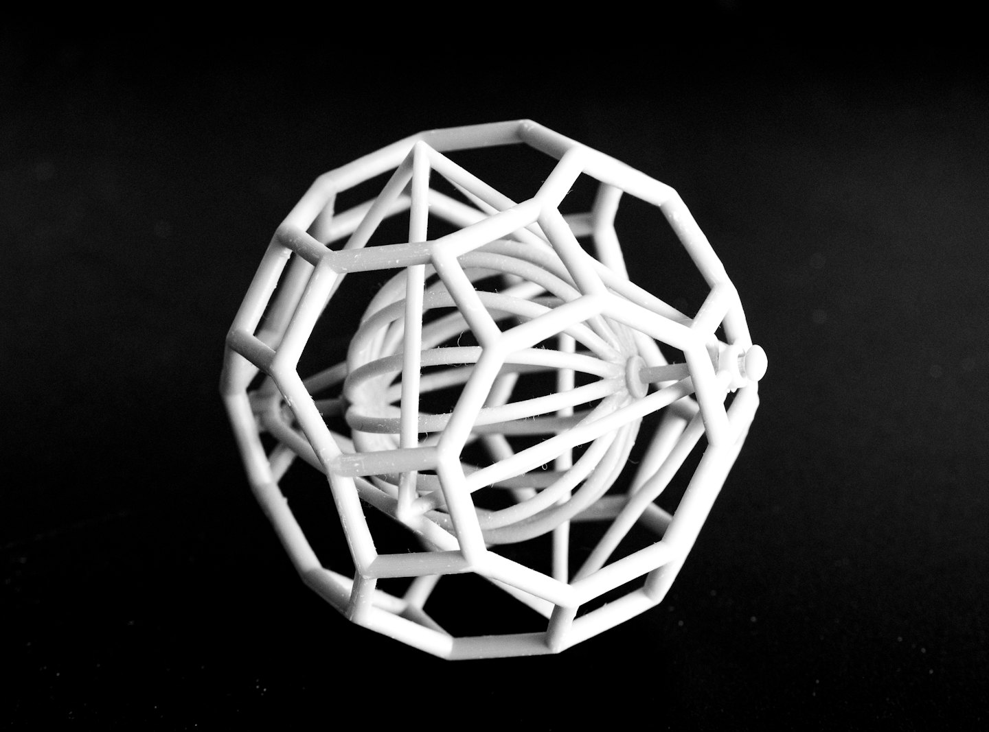 Komplizierte weiße 3D-gedruckte geometrische Kugel auf schwarzem Hintergrund.