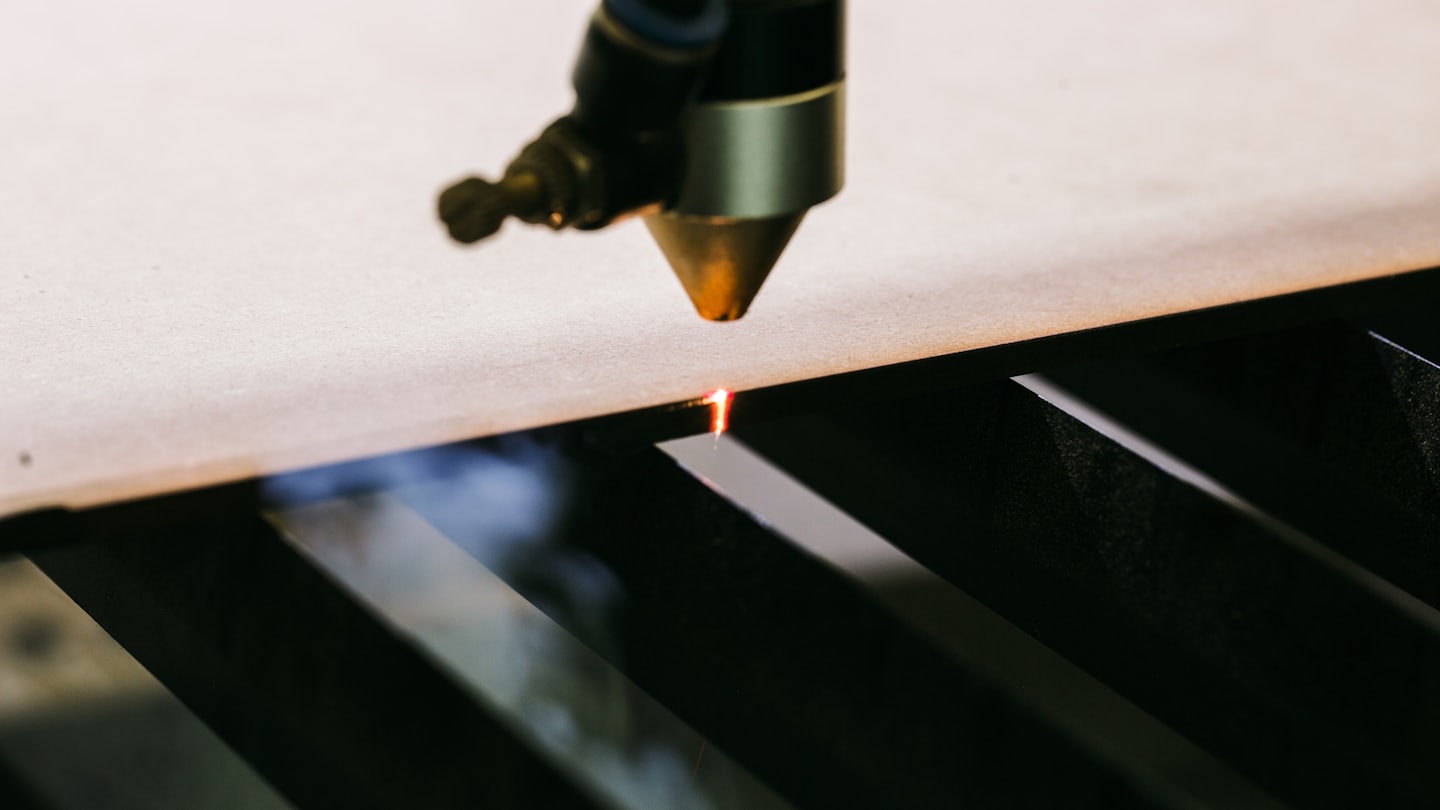 Laserschneider schneidet präzise durch eine helle Materialplatte.