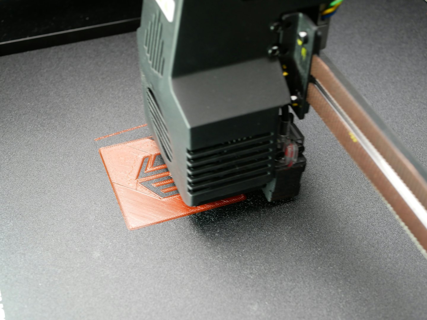 3D-Drucker extrudiert orangefarbenes Filament, um ein kleines Objekt zu erstellen.