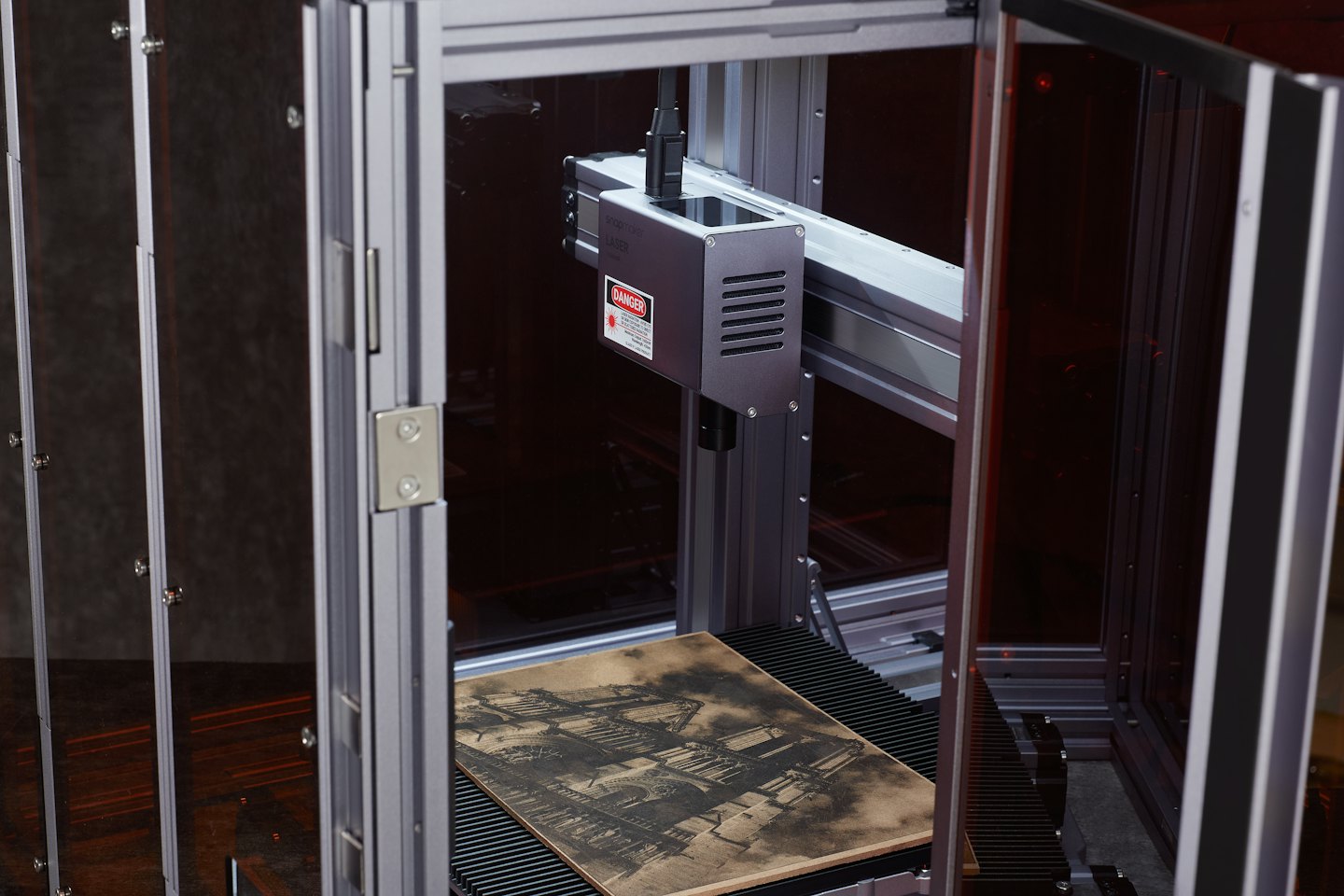 Lasergravurmaschine mit filigranem Design auf Holz.