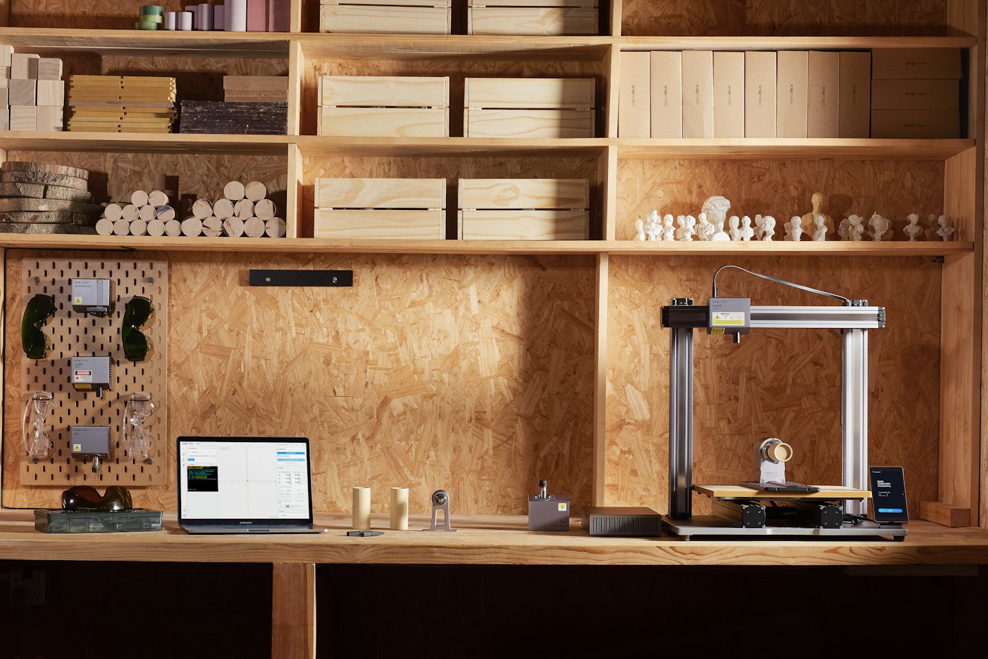 Lasergravierer und 3D-Drucker auf einer Werkbank mit Laptop.
